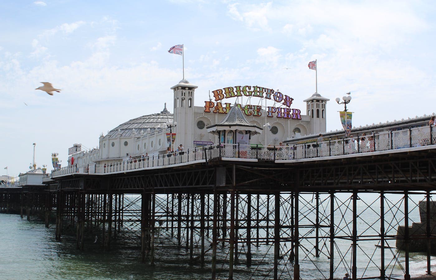 Brighton's colourful beach huts with the West Pier ruins in the distance at golden hour