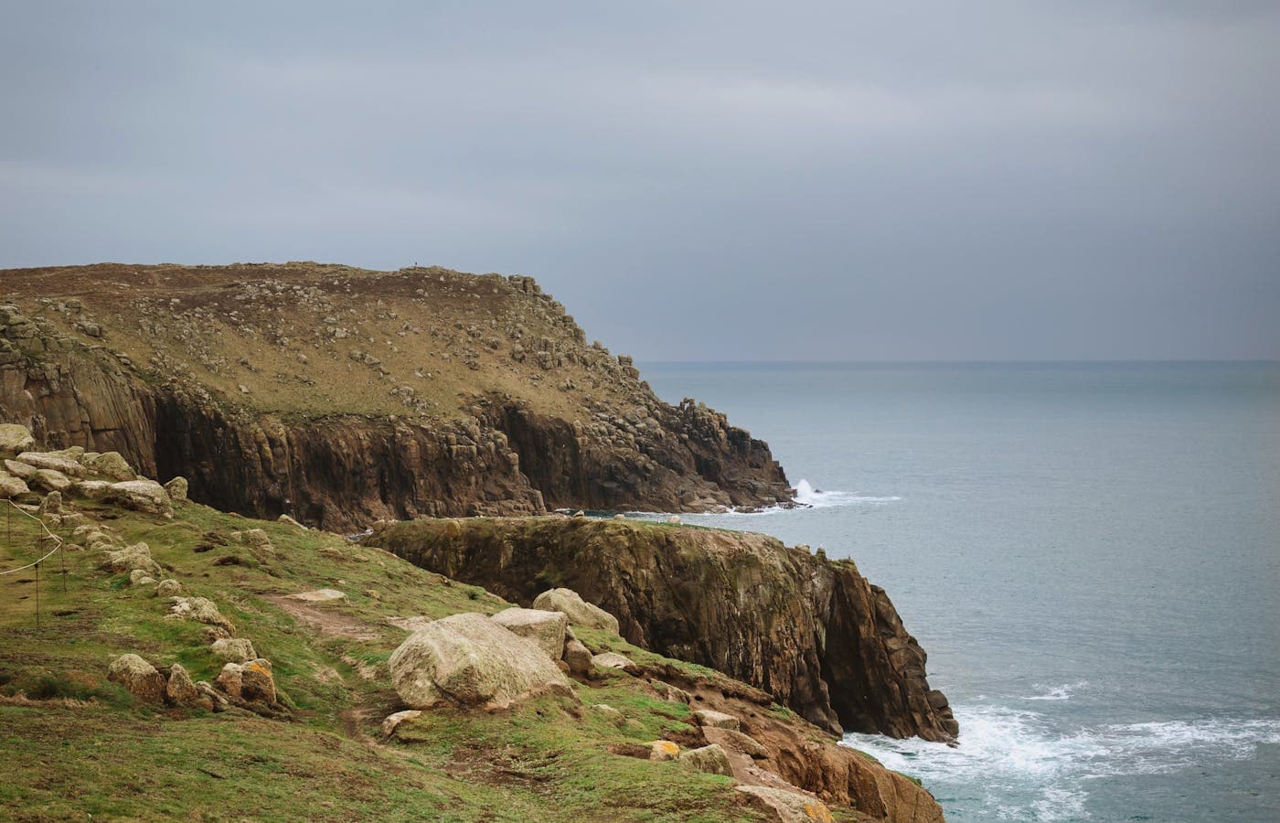 A Cornish cove at low tide with clear turquoise water and a fishing village on the cliff
