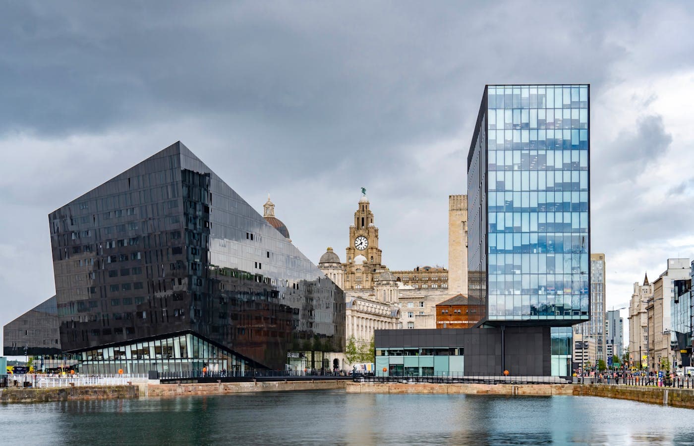 The Liverpool waterfront at dusk with the Three Graces lit against the Mersey sky